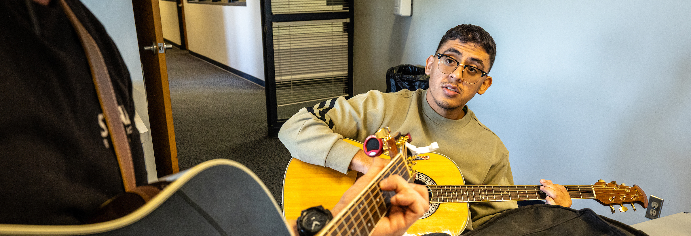 man sitting, holding guitar